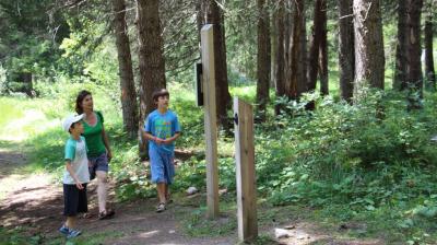 Famille devant un panneau Sentier de l'explorateur en herbe